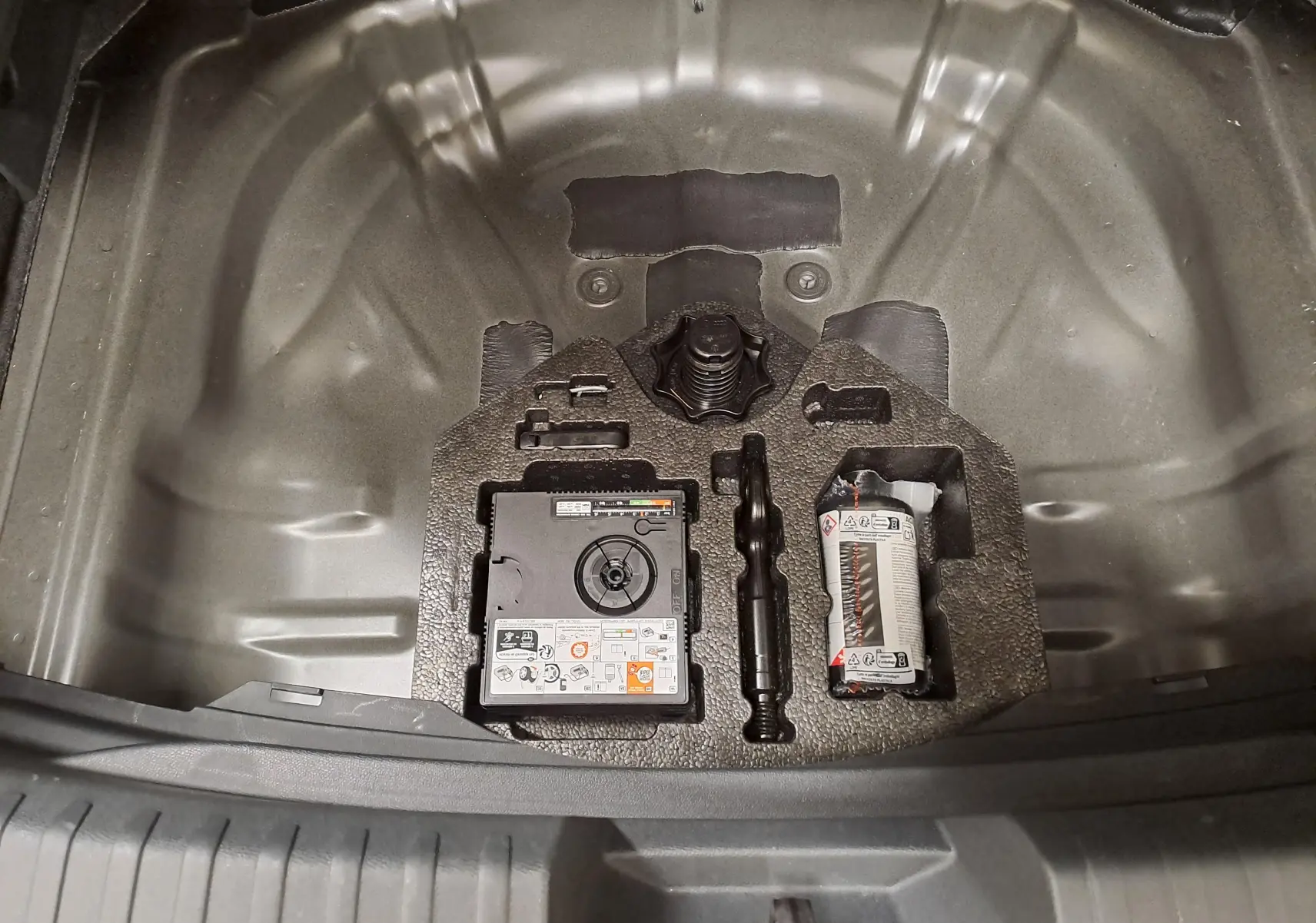 Coffre ouvert vue de dessus montrant le compartiment de rangement avec kit de réparation sur CUPRA Leon Noir Minuit 2025.