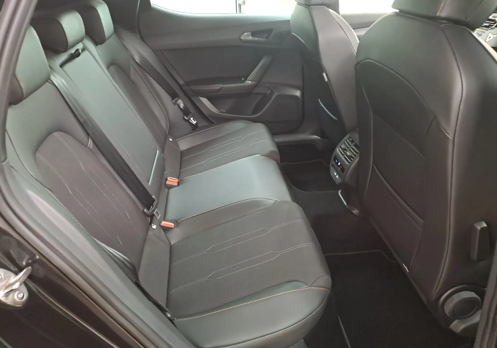 Vue intérieure arrière côté gauche de la CUPRA Leon 2025 avec sièges noirs et surpiqûres contrastantes visibles.