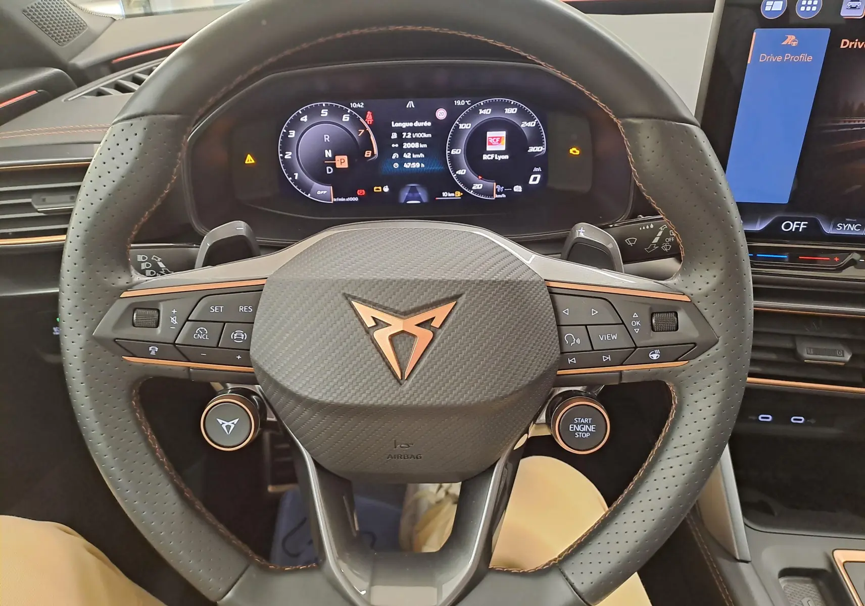 Vue rapprochée du volant perforé noir avec logo CUPRA cuivré et tableau de bord numérique du Leon 1.5 eTSI 2025.