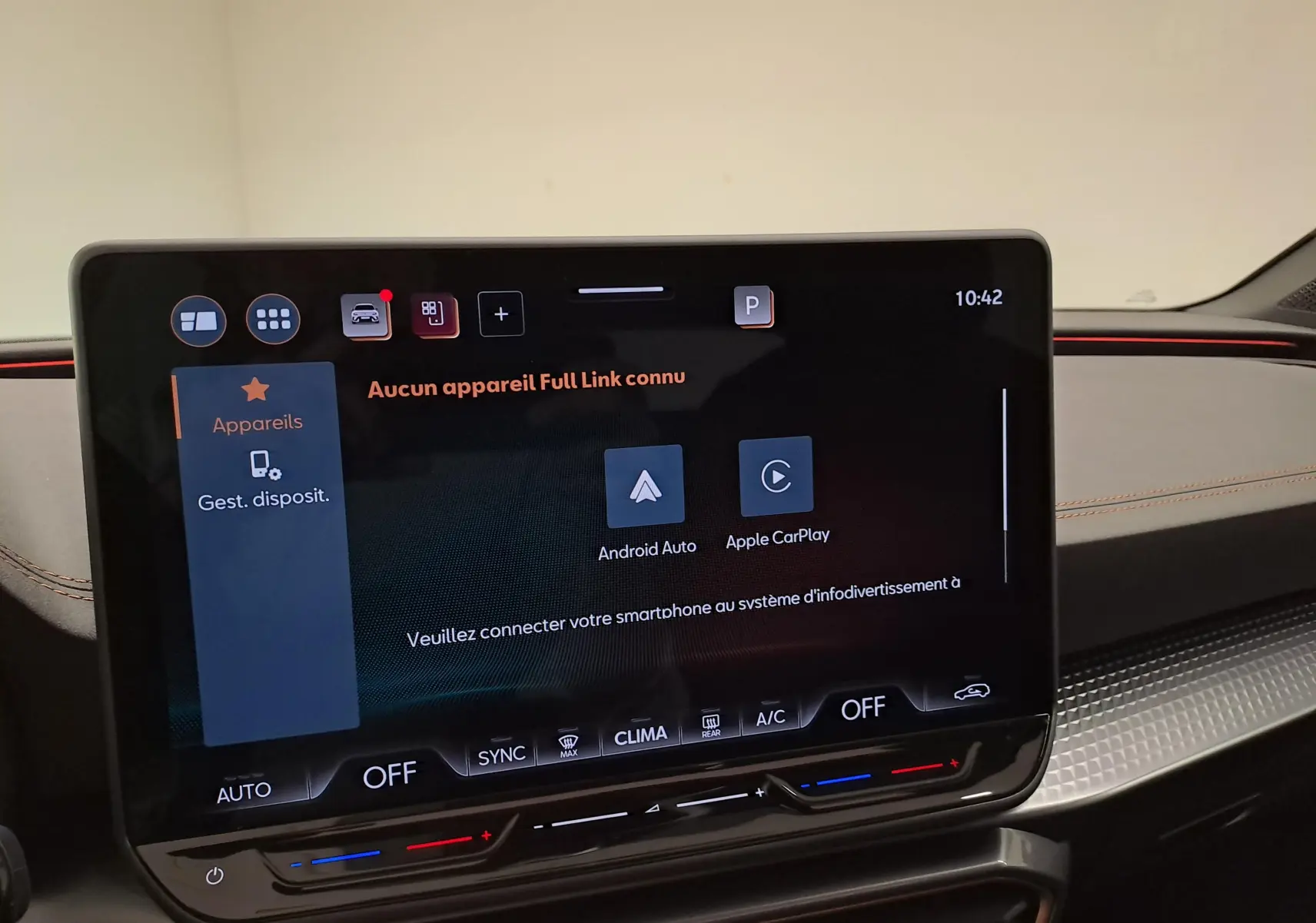 Écran tactile central de la CUPRA Leon 2025 affichant les options Android Auto et Apple CarPlay, avec tableau de bord noir et surpiqûres orange.