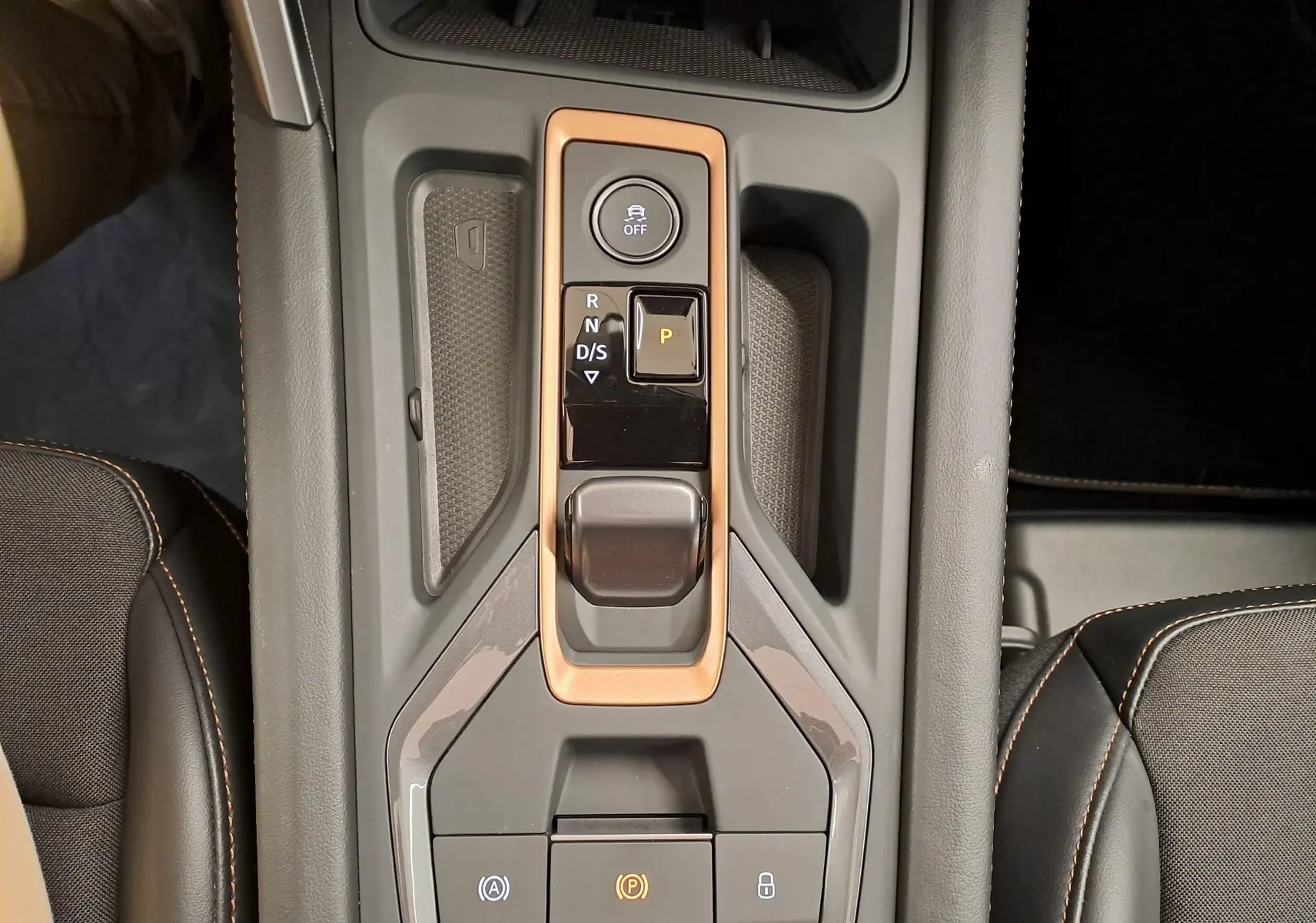Vue plongeante sur la console centrale de la CUPRA Leon 2025, avec commandes de boîte auto et surpiqûres orange visibles.