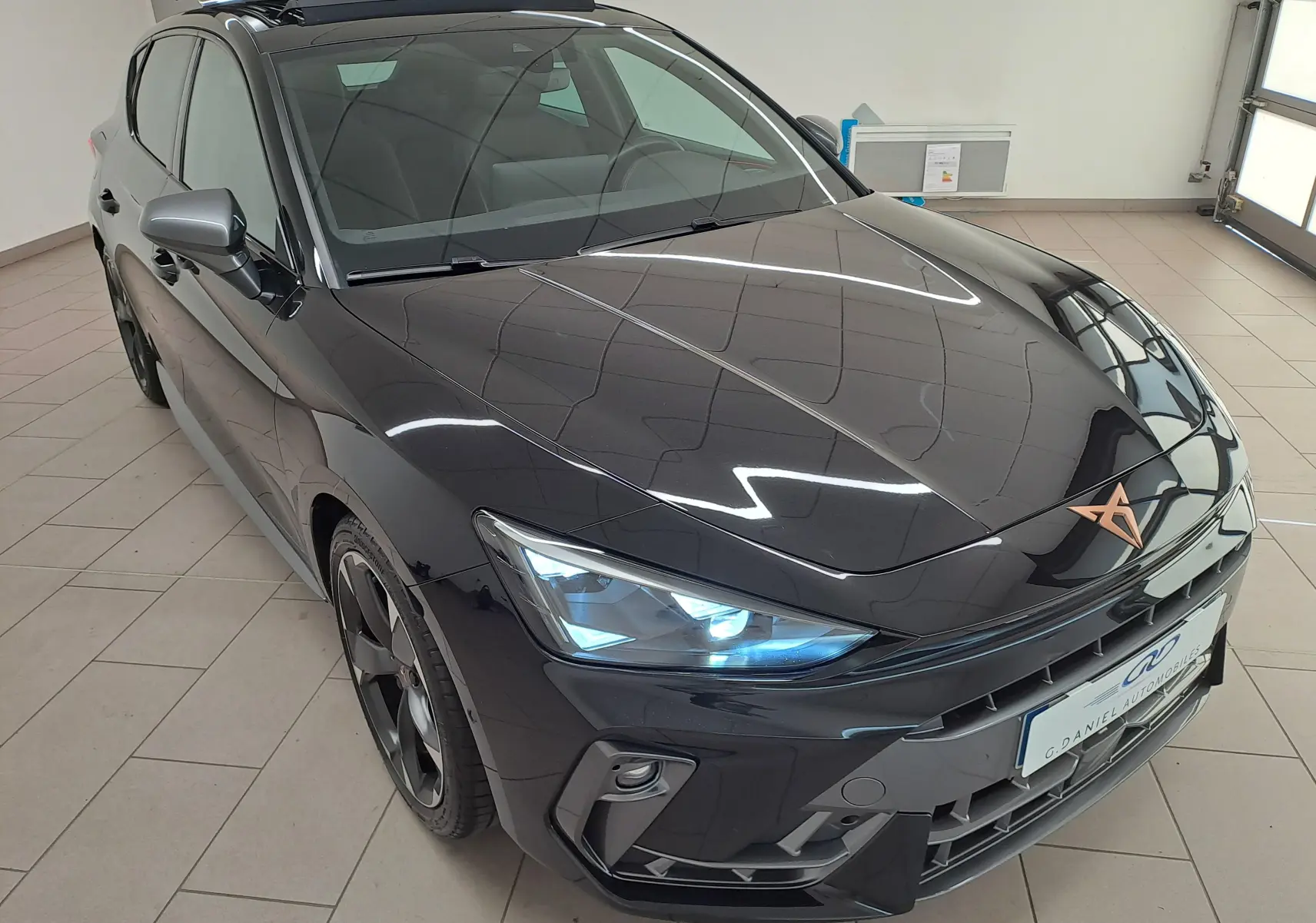 Vue 3/4 avant droite d'une CUPRA Leon 2025 Noir Minuit avec projecteurs Matrix LED et toit ouvrant panoramique.