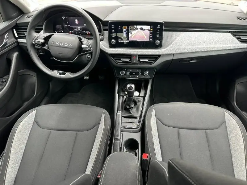 Vue intérieure avant de la Skoda Scala 2025 avec tableau de bord moderne, volant cuir multifonction et sièges tissu noir/gris.