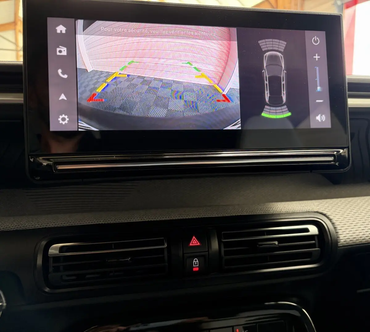 Écran tactile central affichant la caméra de recul et l'aide au stationnement dans l'habitacle d'une Citroën C3 rouge.