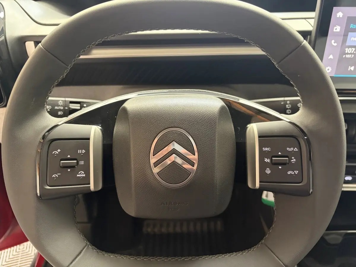 Gros plan sur le volant cuir multifonctions de la Citroën C3 Turbo 100 BVM6 MAX rouge, avec commandes intégrées.
