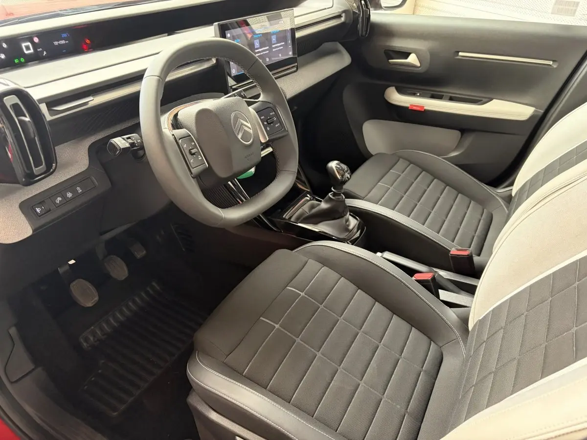 Intérieur de la Citroën C3 Turbo 100 BVM6 2025 vu côté conducteur, sièges bi-ton noirs et gris, volant cuir multifonctions.