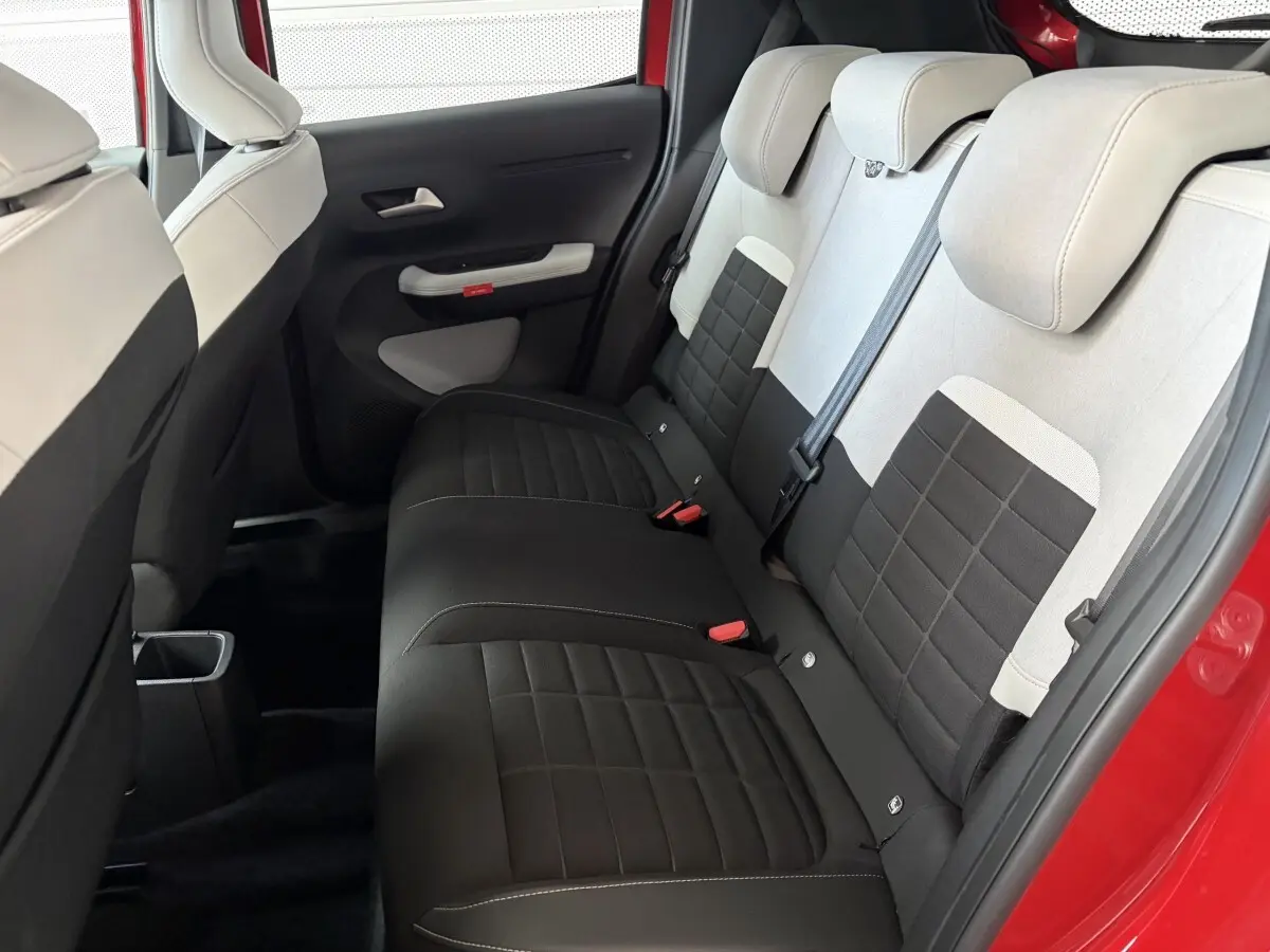 Vue intérieure côté arrière droit de la banquette arrière bicolore noire et beige d'une Citroën C3 rouge 2025.