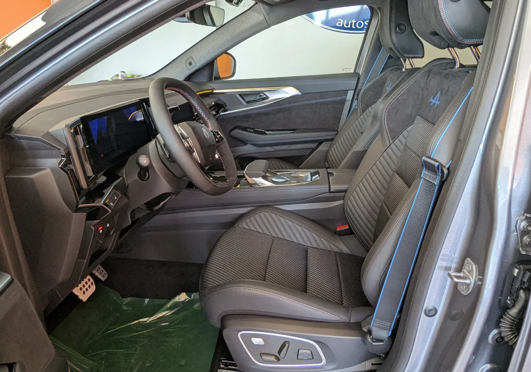 Vue intérieure côté conducteur du Renault Austral E-Tech 200 Esprit Alpine gris schiste, sièges en TEP/Alcantara avec surpiqûres bleues et logo Alpine.