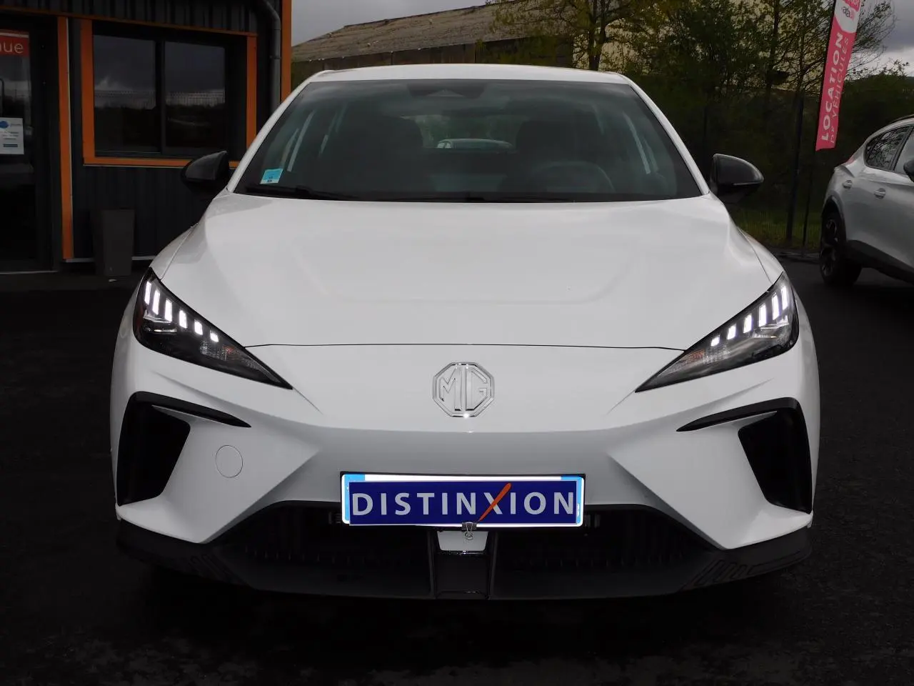 Vue de face du MG4 blanc électrique avec ses phares LED allumés et calandre épurée.