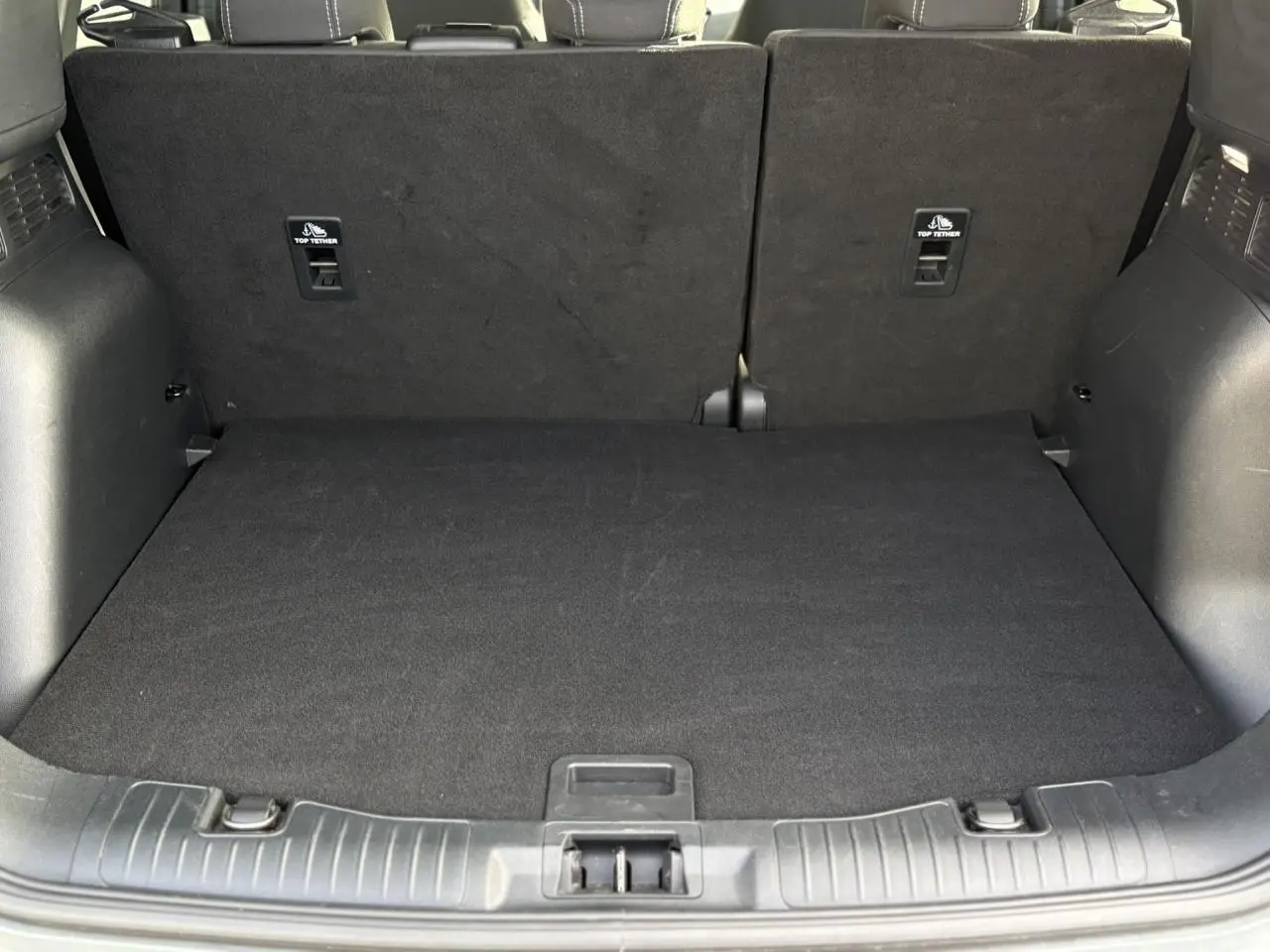 Coffre spacieux du Ford Kuga 2024 gris Solar vu de l'arrière avec sièges arrière relevés et plancher plat.