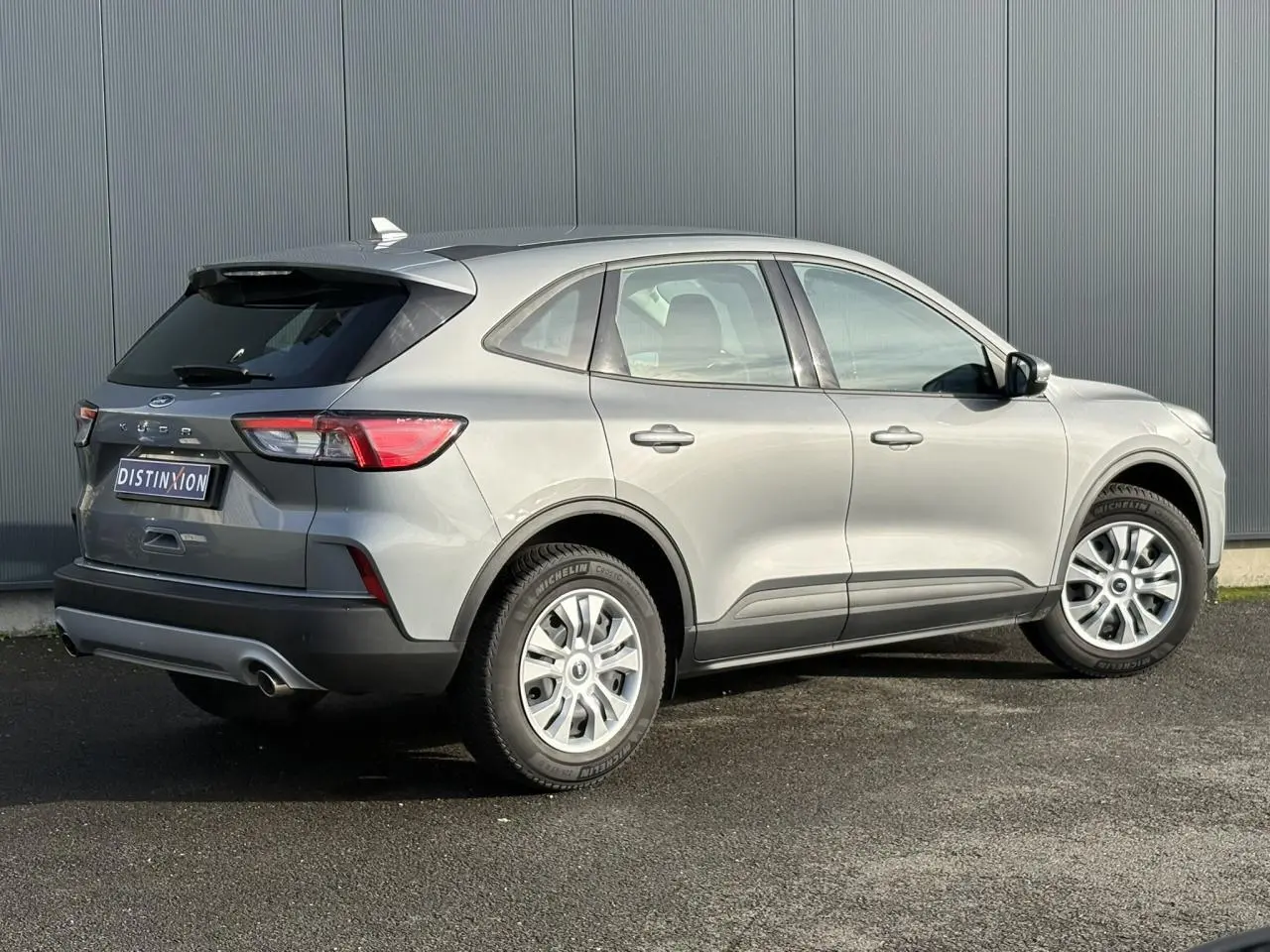 Vue 3/4 arrière droite d'un Ford Kuga 2024 gris Solar avec jantes alliage et feux arrière LED distinctifs.