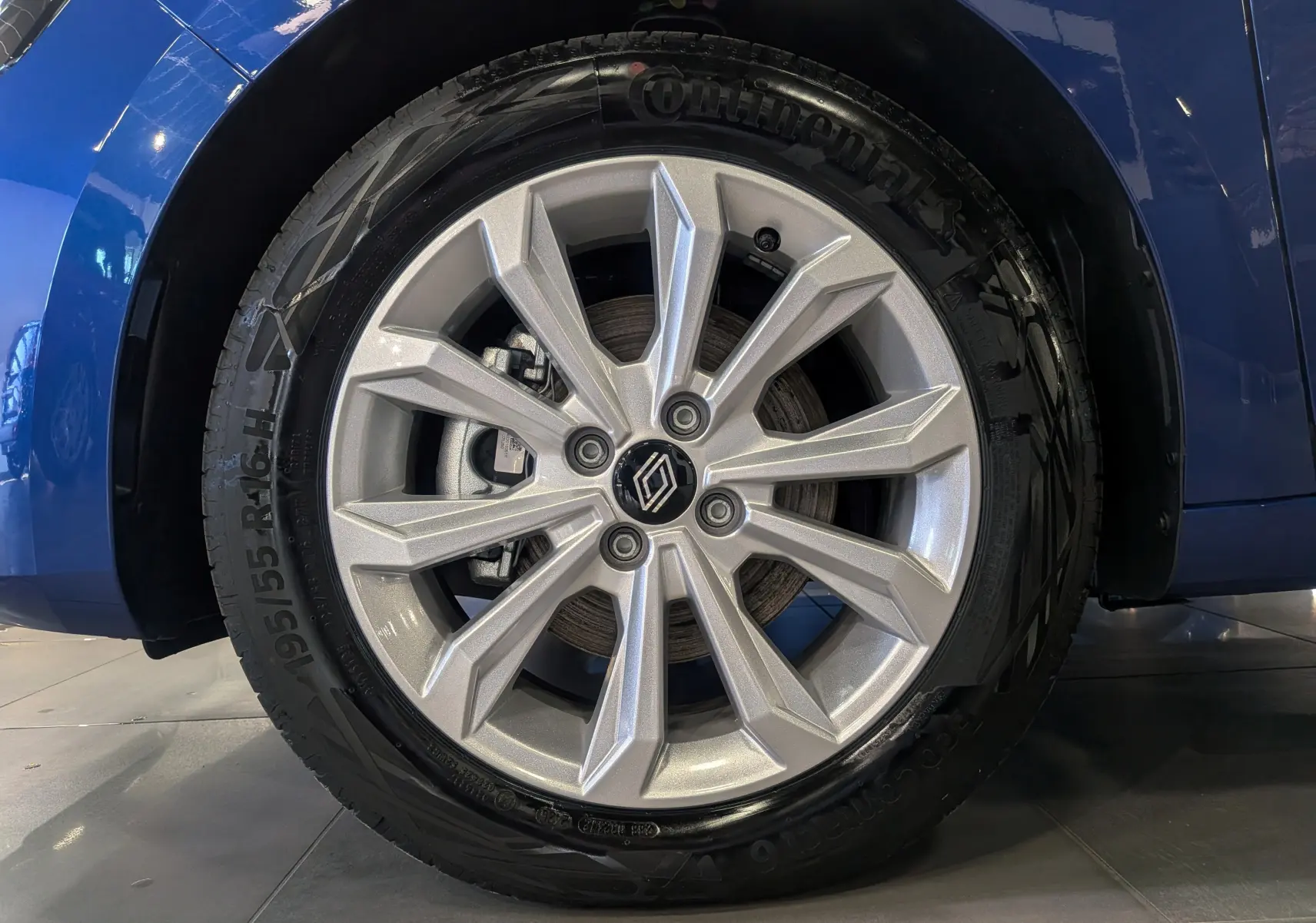 Gros plan sur la roue avant droite de la Renault Clio V Bleu Iron, jante alliage argentée à design moderne.