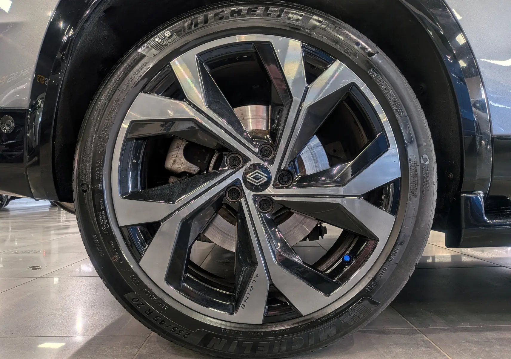 Gros plan sur la roue avant droite du Renault Austral E-Tech hybrid 200 Iconic esprit Alpine, jante biton noire et argent.