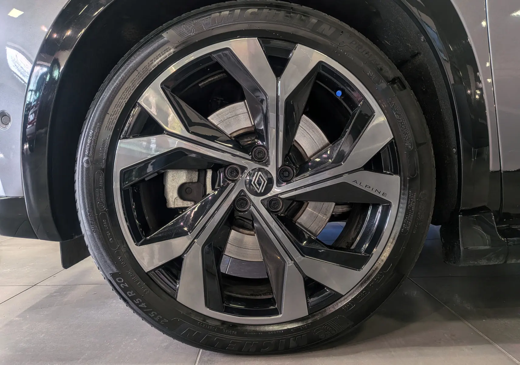 Gros plan sur la jante avant droite biton noir et gris du Renault Austral E-Tech hybrid 200 Iconic esprit Alpine gris Schiste.