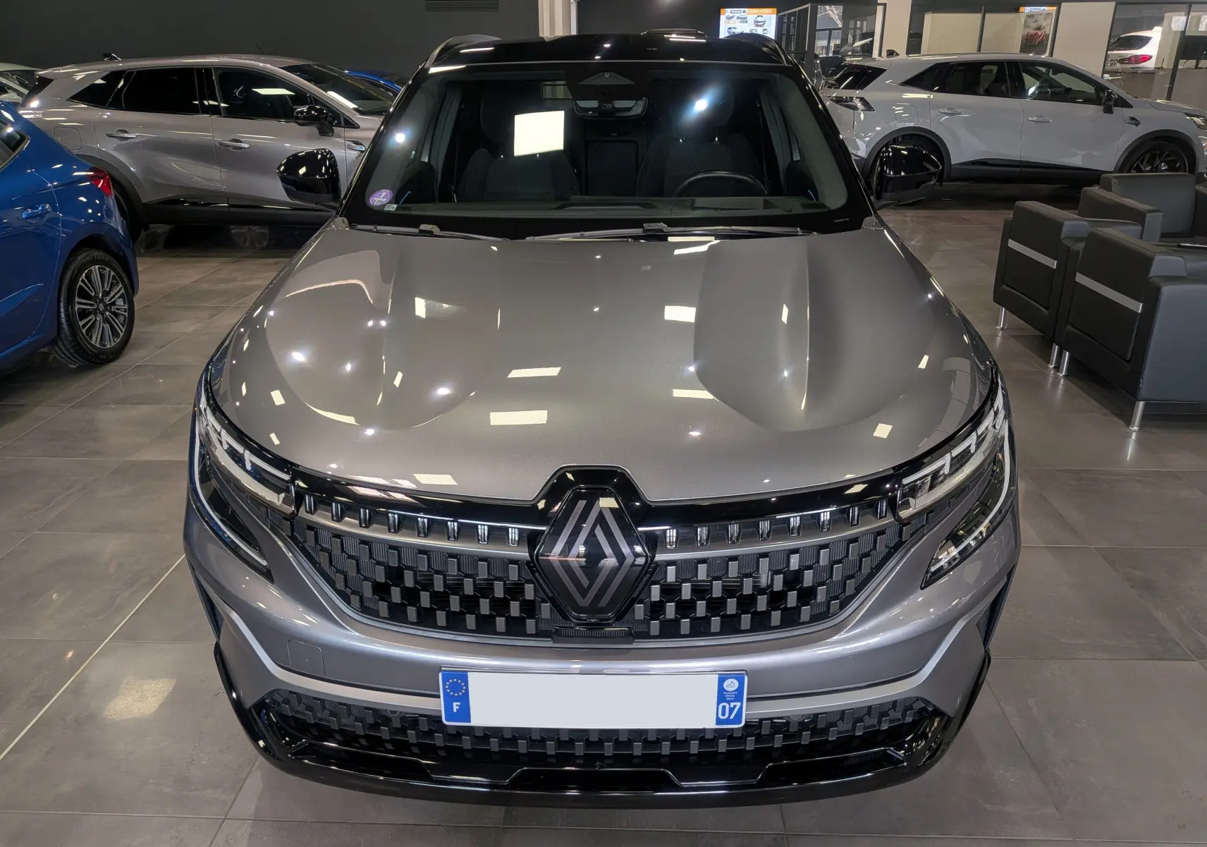 Vue avant d'un Renault Austral E-Tech hybrid 200 Iconic gris schiste avec toit noir, calandre et logo Renault bien visibles.