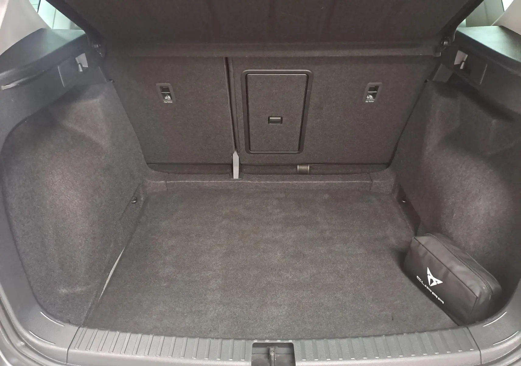 Coffre ouvert du SEAT Ateca gris graphite 2023, montrant un espace de chargement vide avec une trousse noire sur la droite.