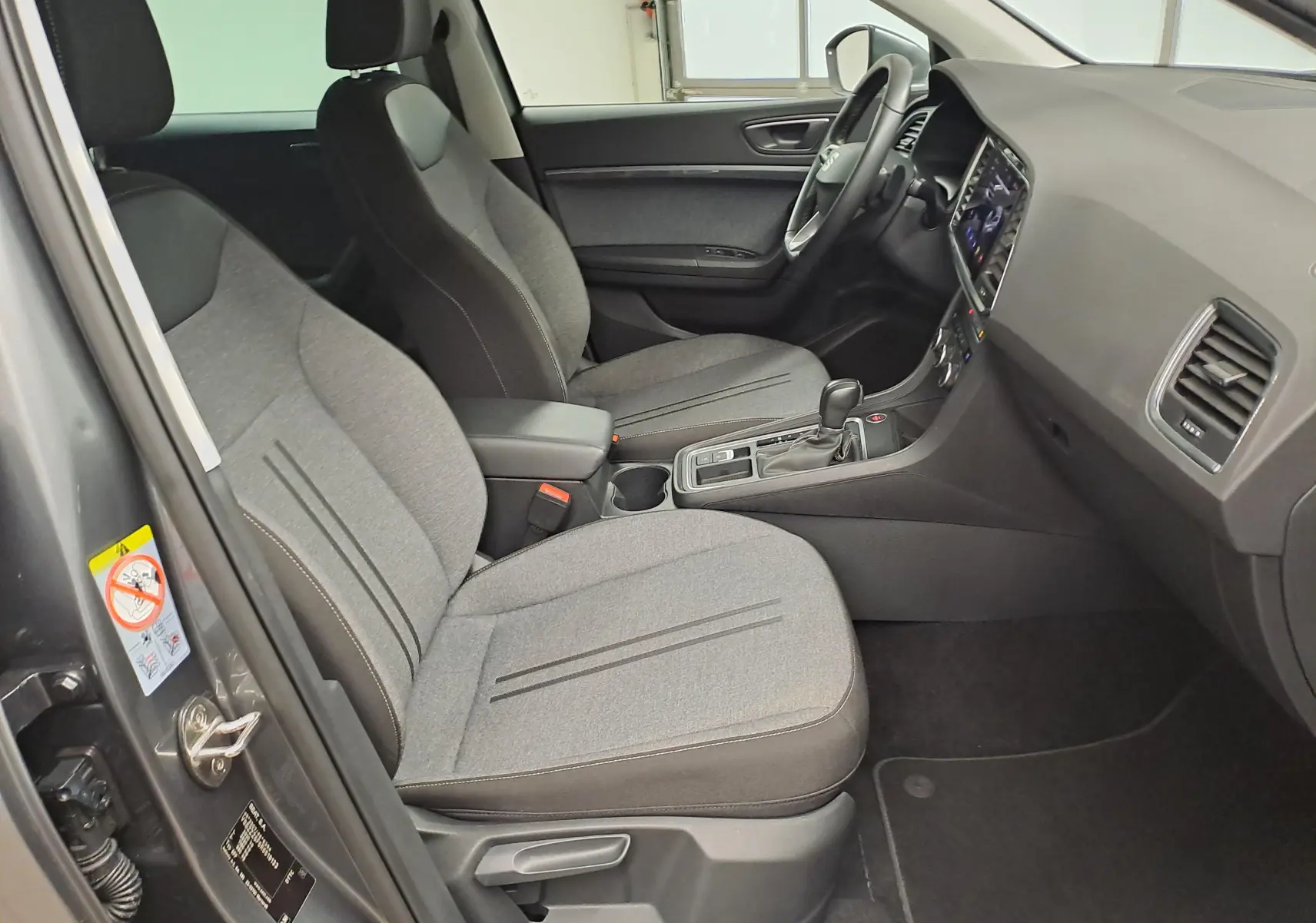 Vue intérieure côté conducteur du SEAT Ateca 2023 gris graphite, sièges tissu gris et console centrale avec boîte auto DSG7.