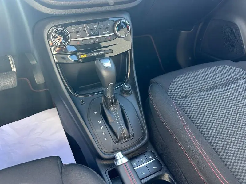 Gros plan sur la console centrale et le levier de vitesse automatique du Ford Puma gris Solar Métallisée, intérieur tissu à surpiqûres rouges.