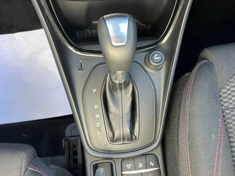 Gros plan sur le levier de vitesses automatique noir du Ford Puma 2023, avec bouton de siège chauffant et coutures rouges visibles.