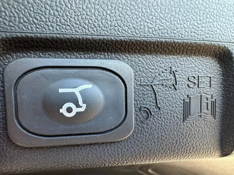 Bouton de réglage ouverture hayon avec pictogramme sur tableau de bord en plastique noir texturé d'une Ford Puma gris Solar Métallisée.