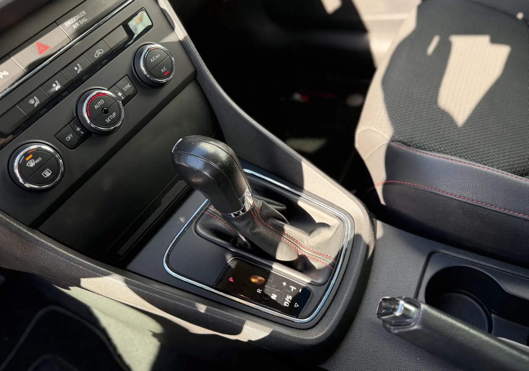 Gros plan sur la console centrale du SEAT LEON blanc, mettant en valeur le levier de vitesse automatique et les commandes de climatisation.