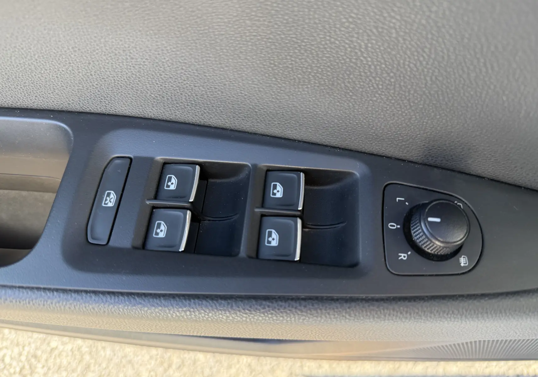 Gros plan sur les commandes des vitres électriques et réglages des rétroviseurs côté conducteur d’une SEAT LEON blanc 2014.