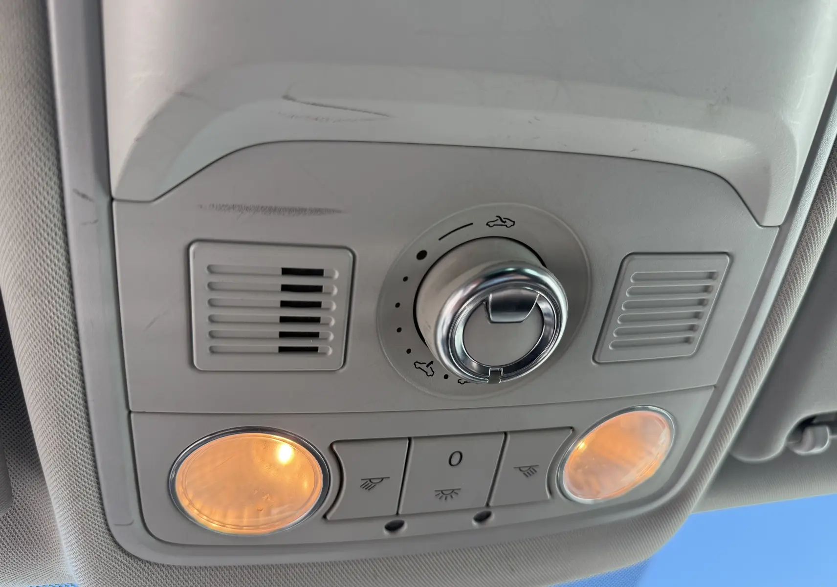 Vue en gros plan du plafonnier intérieur gris clair avec commandes d'éclairage et ventilation dans une SEAT Leon blanche.