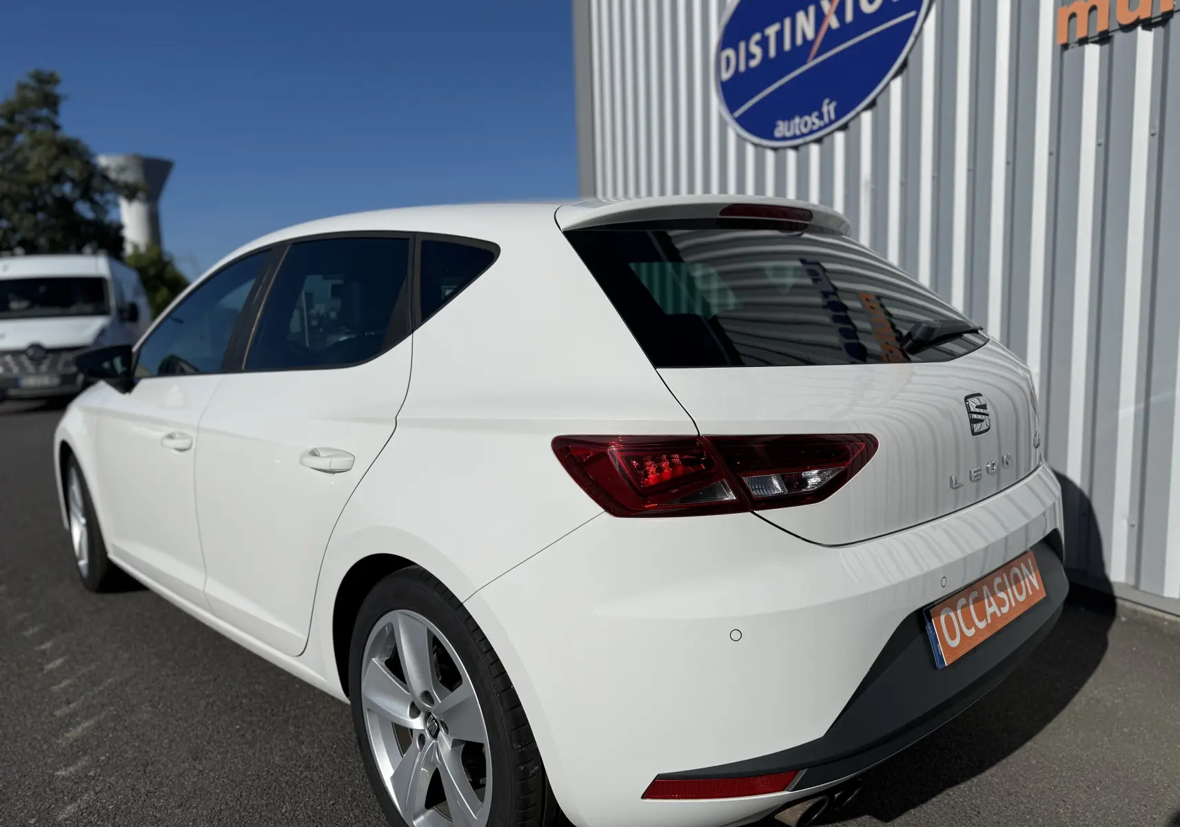 SEAT Leon blanc vue 3/4 arrière droit, avec feux arrière LED et jantes alliage 17 pouces visibles.