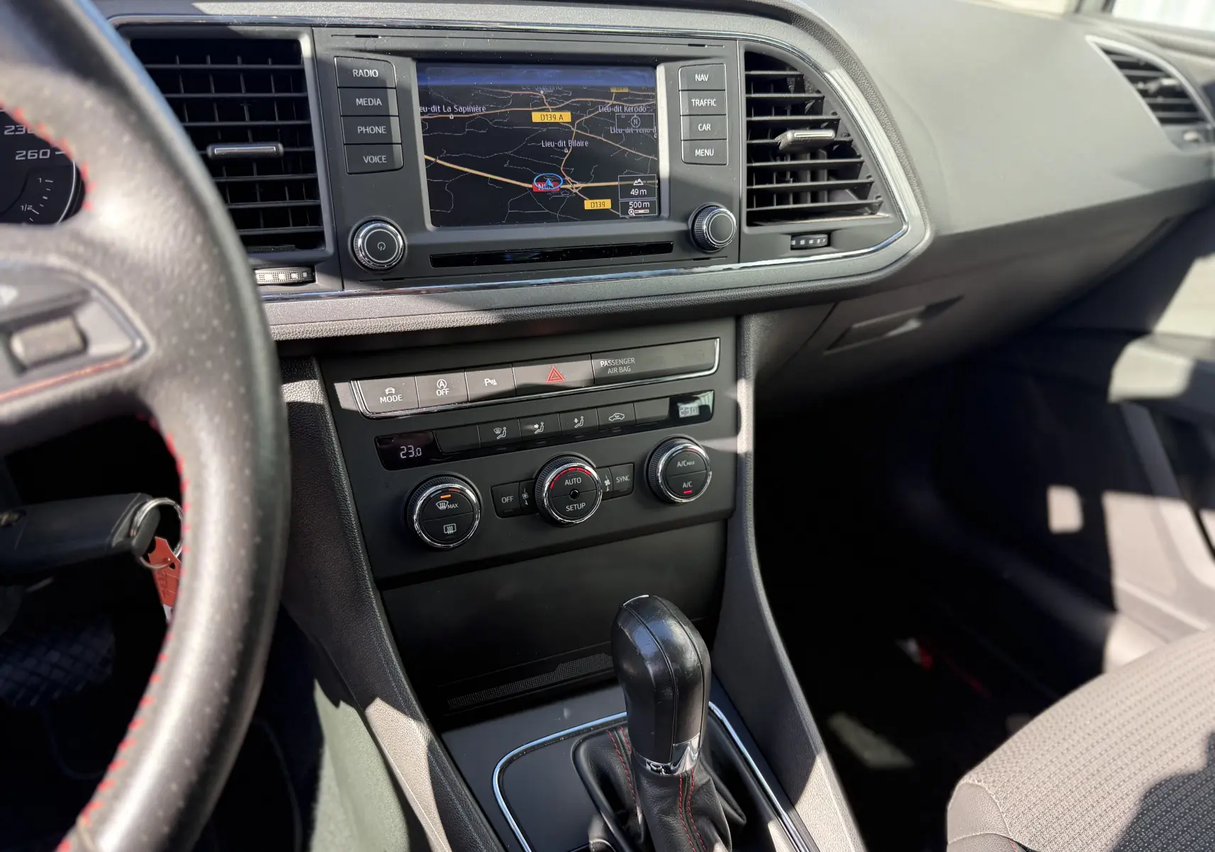 Vue intérieure centrée sur la console centrale d'une SEAT LEON 1.8 TFSI 2014, avec écran de navigation et levier de boîte auto.