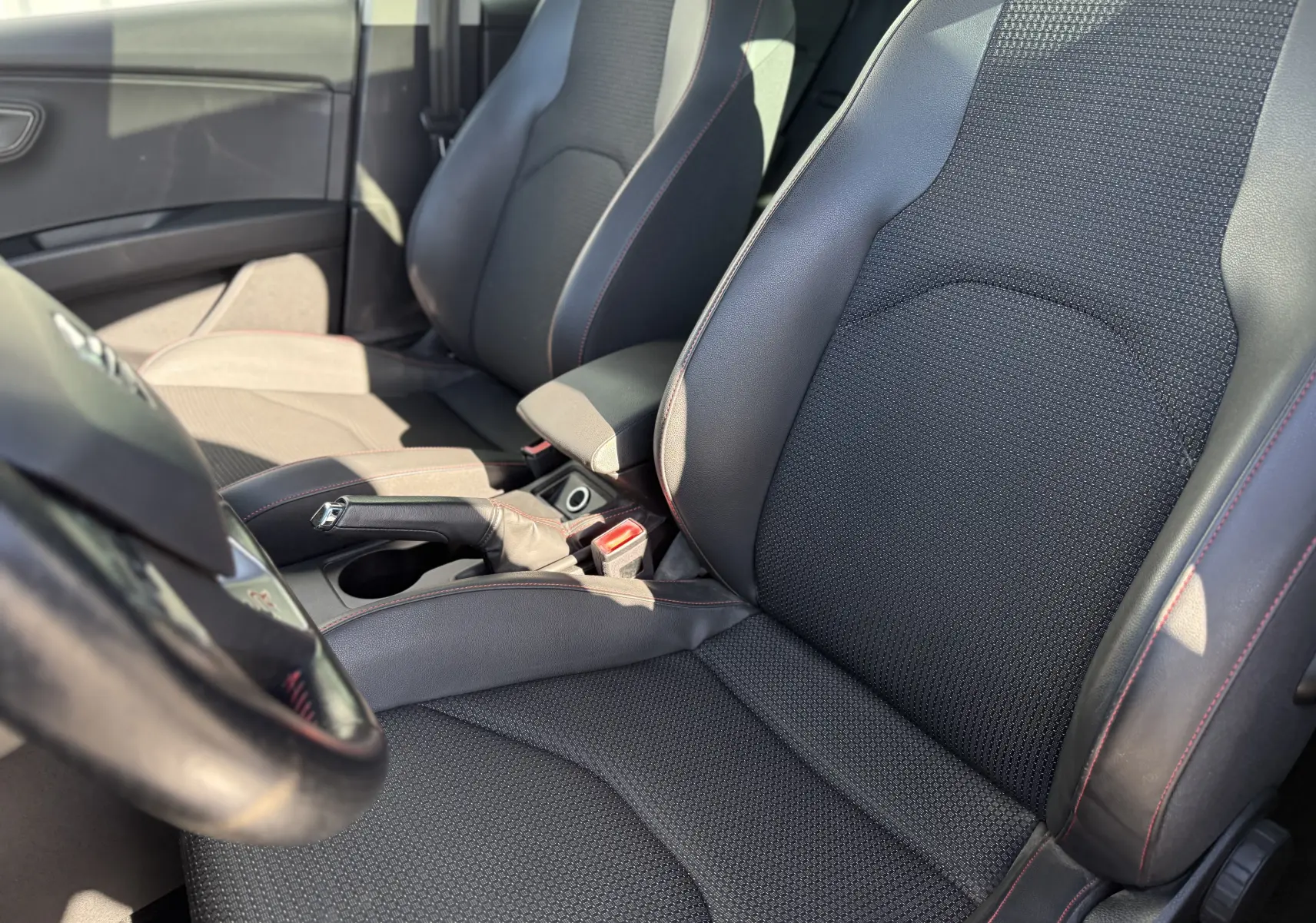 Vue intérieure côté conducteur du siège avant noir avec surpiqûres rouges d'une SEAT Leon 1.8 TFSI 180 FR blanche de 2014.