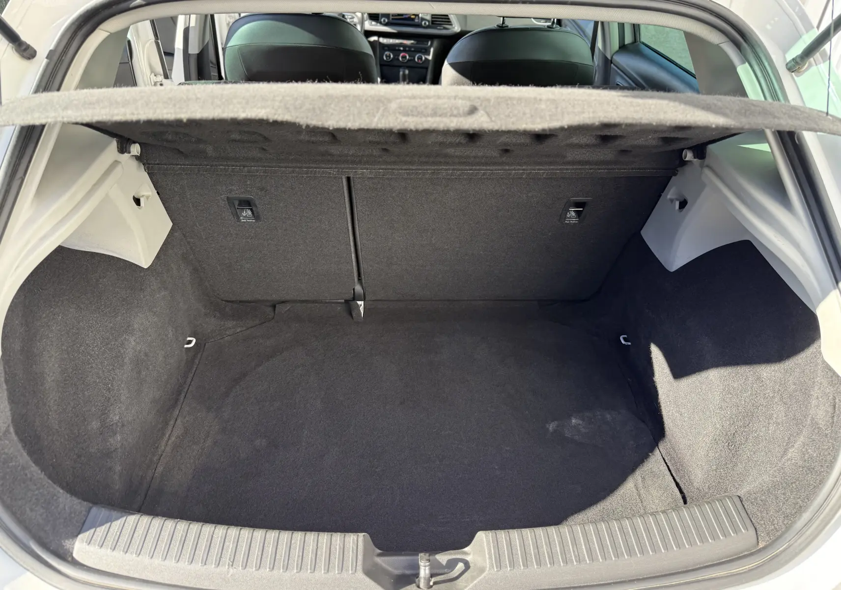 Coffre ouvert vu de l'arrière d'une SEAT LEON blanc 2014, intérieur noir avec banquette arrière visible.