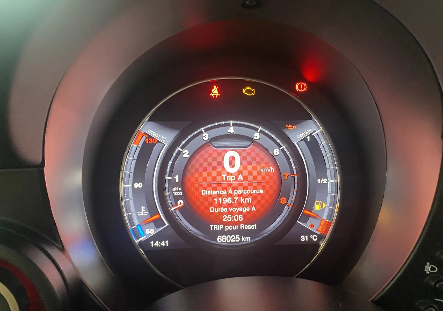 Tableau de bord numérique de l'Abarth 595 noir, affichant le compteur à 0 km/h et plusieurs voyants allumés.