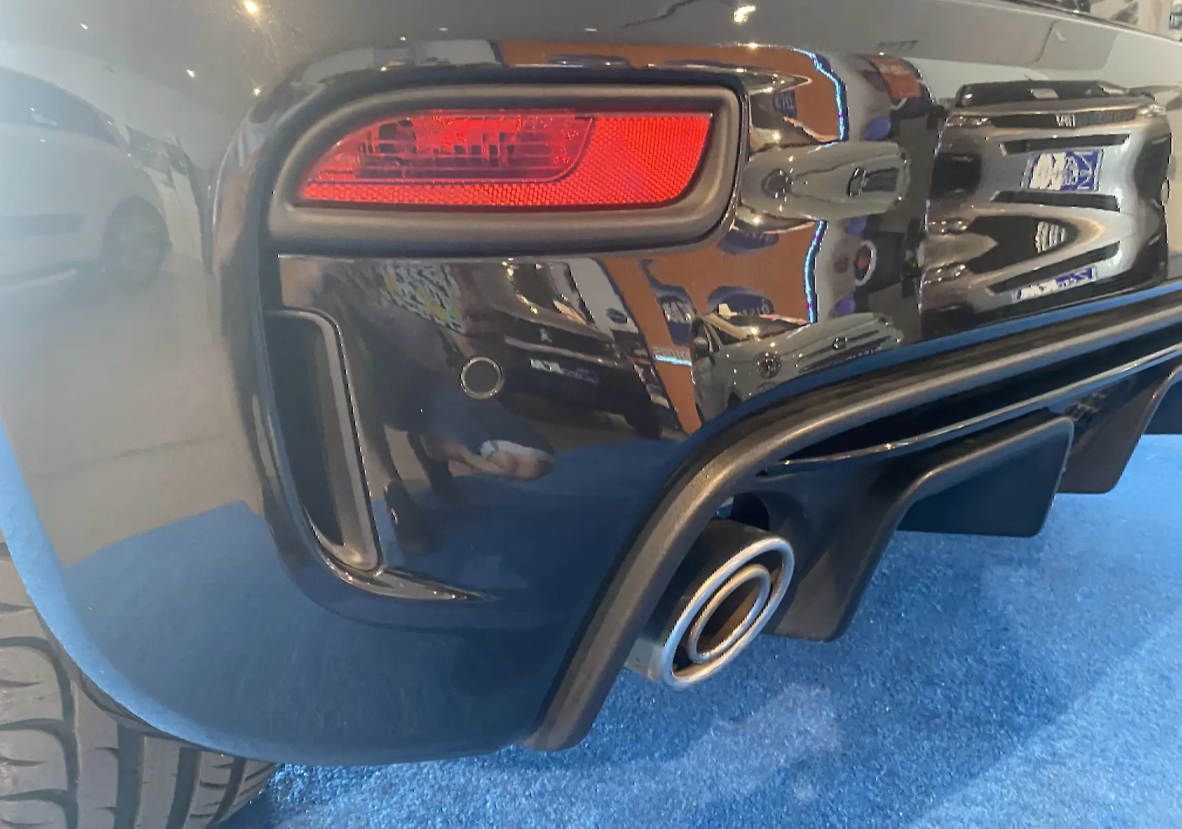 Gros plan sur le feu arrière droit et la sortie d’échappement d’une ABARTH 595 noire, finition brillante.