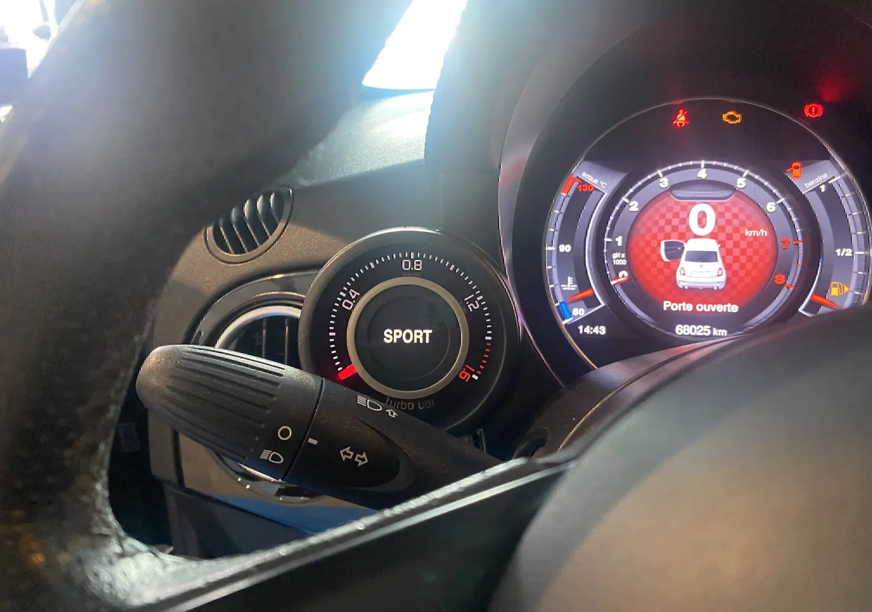 Gros plan sur le tableau de bord numérique de l'Abarth 595 noir, affichant mode Sport et porte ouverte.