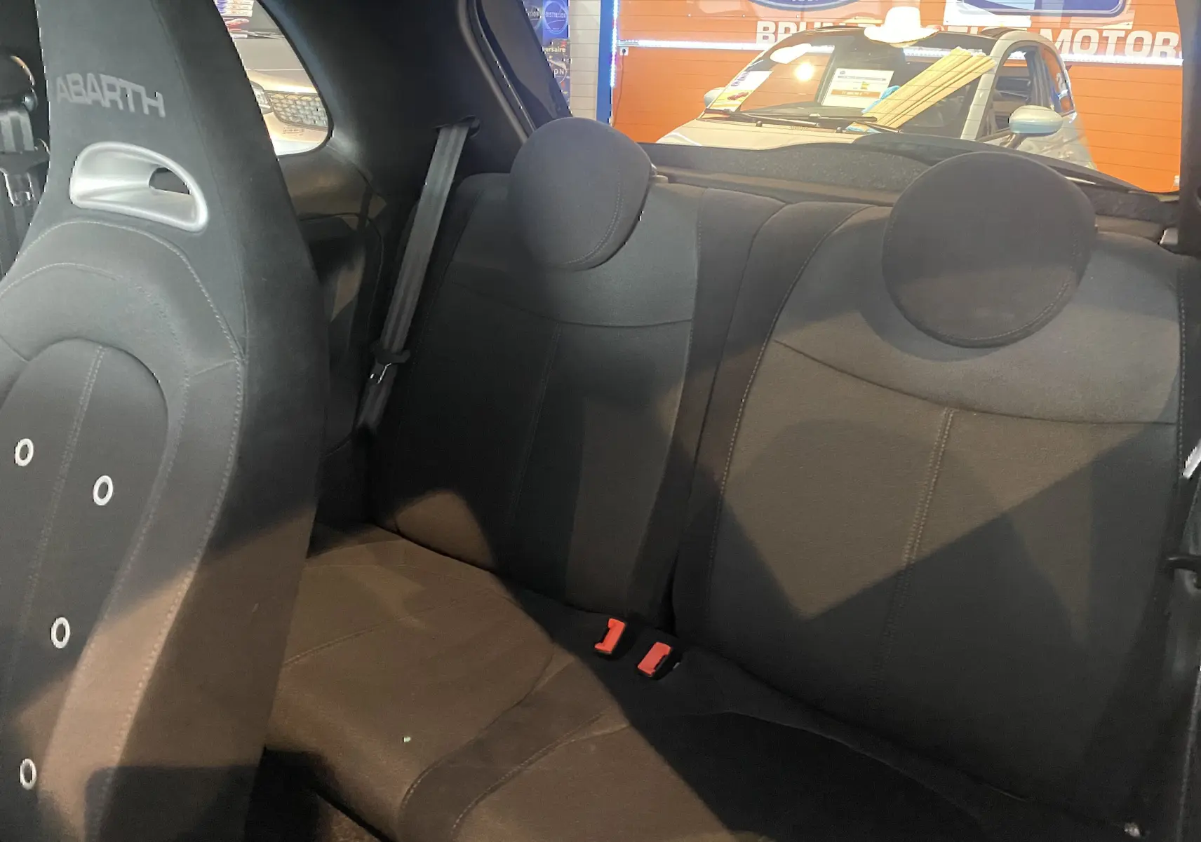 Vue intérieure sur la banquette arrière noire et le siège avant ABARTH d'une 595 2018 avec toit ouvrant visible en arrière-plan.