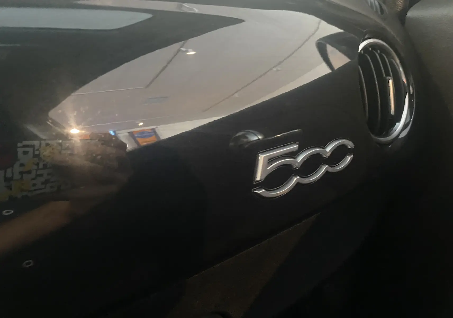 Gros plan sur le tableau de bord noir brillant de l'Abarth 595 avec le logo "500" et une sortie d'air ronde à droite.