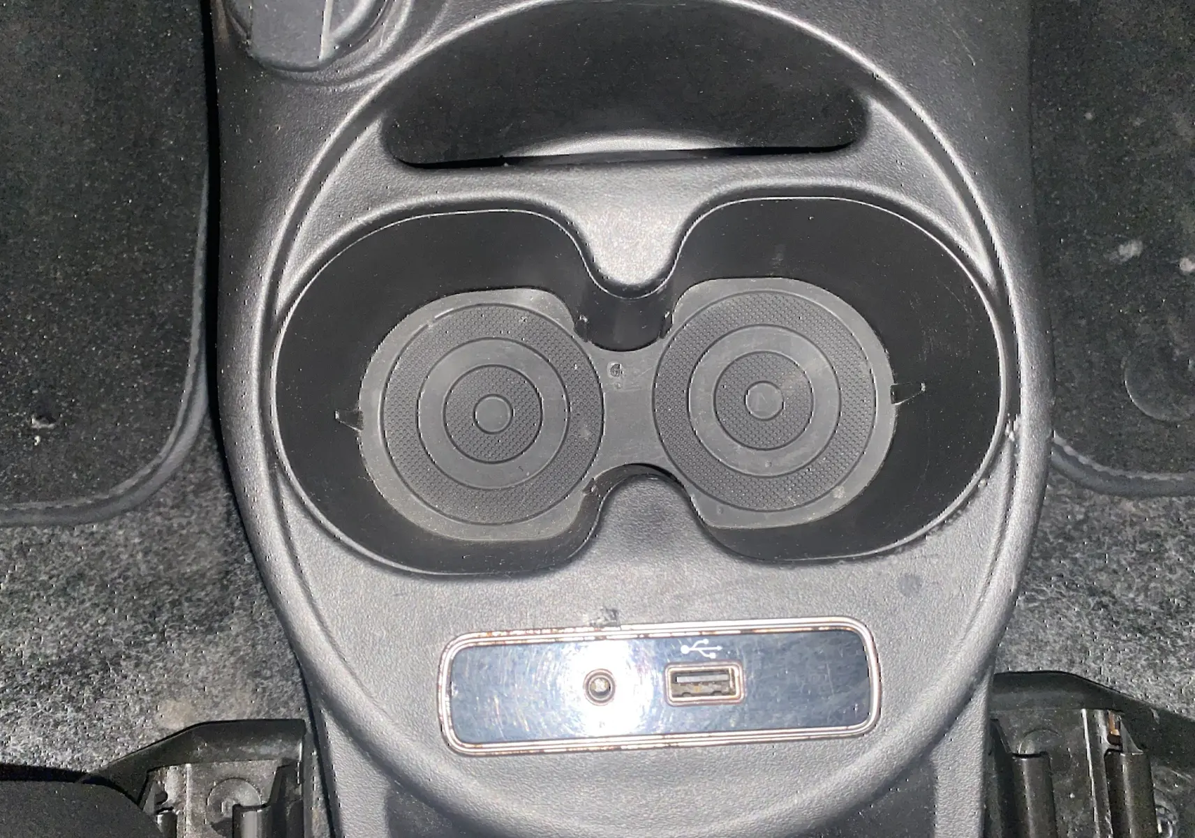 Gros plan sur les porte-gobelets et prise USB de la console centrale d'une ABARTH 595 noire de 2018.