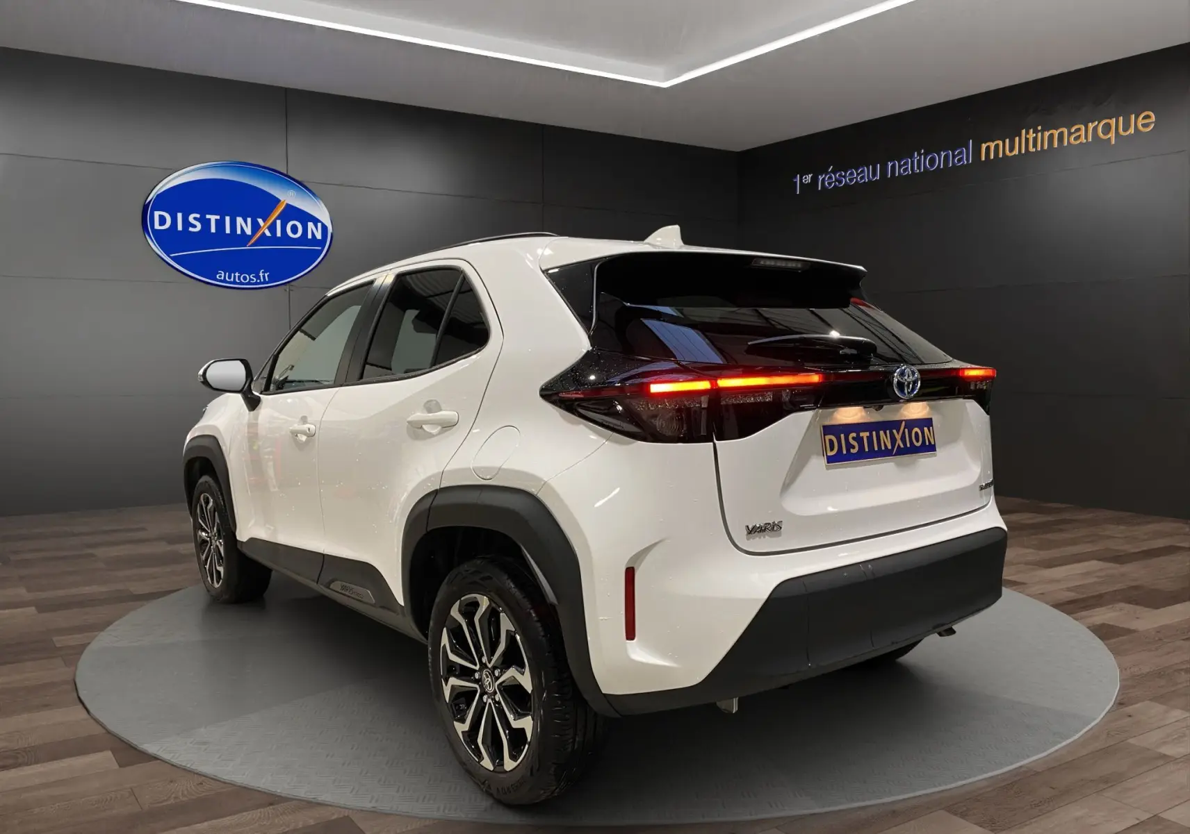 Vue 3/4 arrière droite d'une Toyota Yaris Cross blanche avec feux arrière LED allumés et jantes alu 17 pouces.