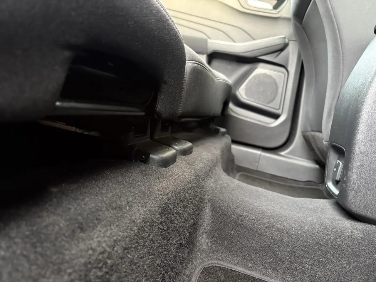Vue en contre-plongée de l'espace au sol arrière côté droit du Ford Kuga 2024 gris Solar, montrant la moquette et la base des sièges.