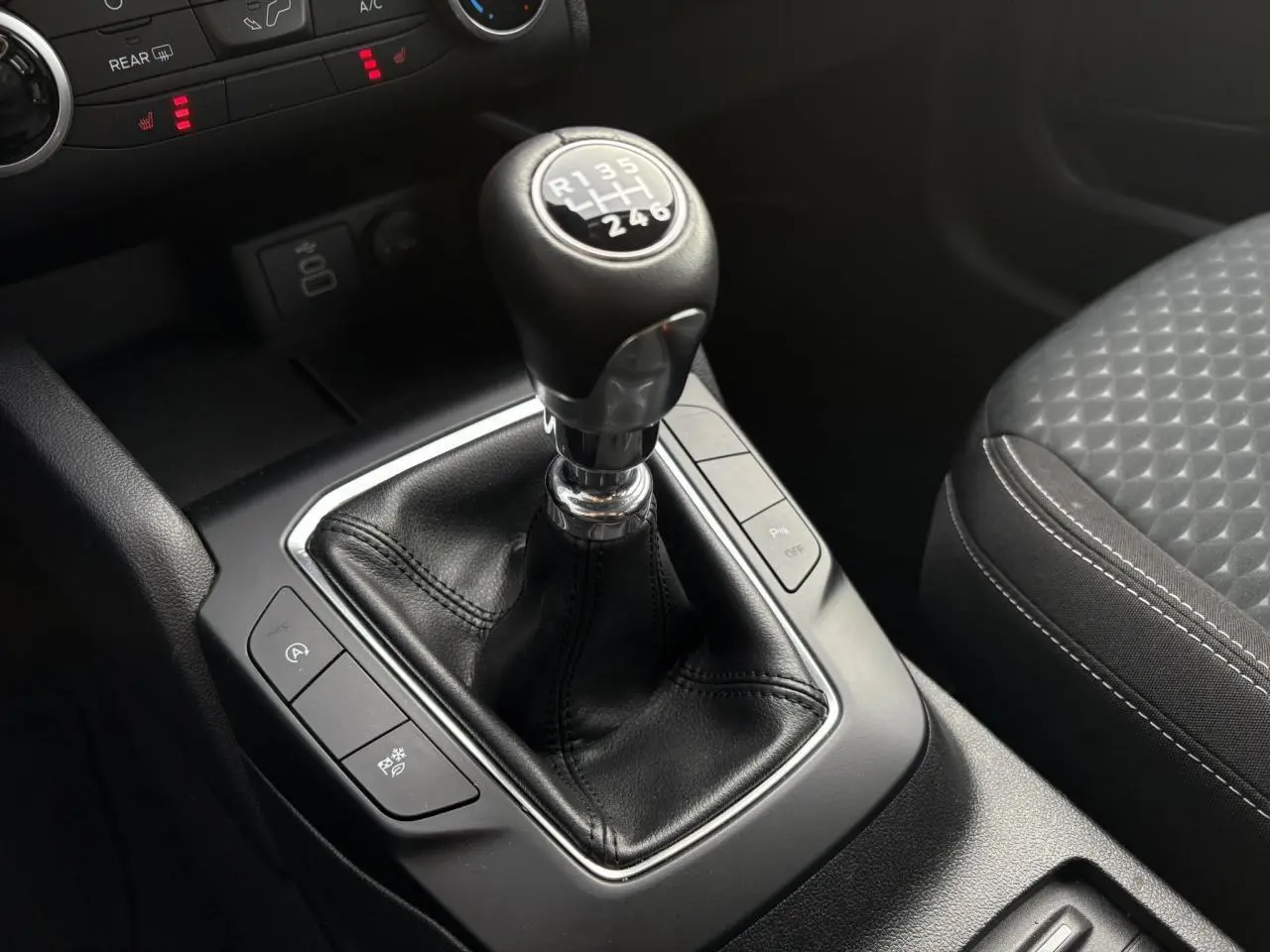 Gros plan sur le levier de vitesses manuel noir et la console centrale du Ford Kuga 2024, avec siège avant gris à motifs.