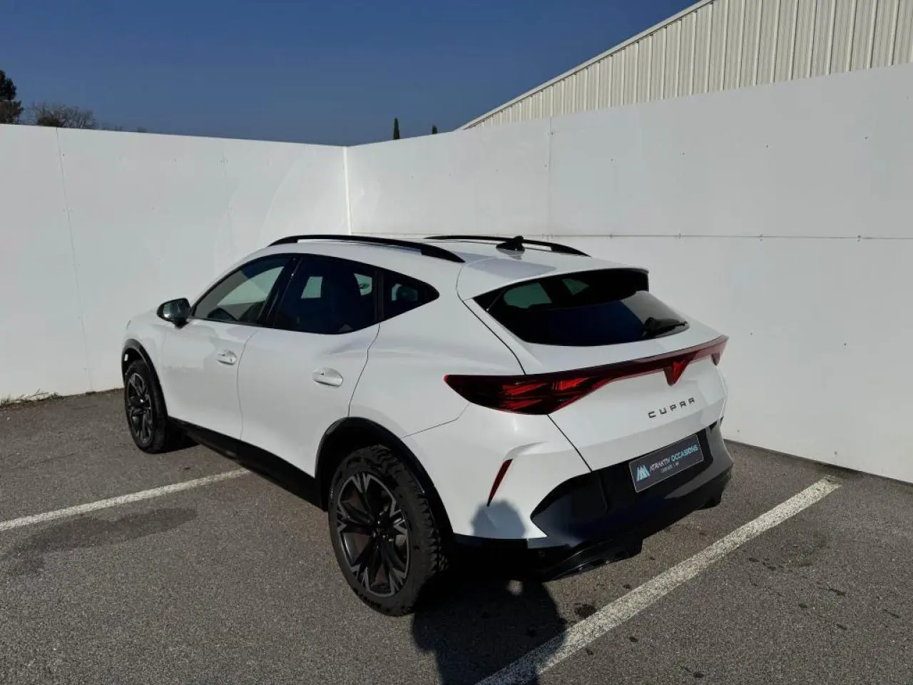 Vue 3/4 arrière droite d’un CUPRA Formentor blanc nacré avec toit noir et jantes alliage noires en extérieur.