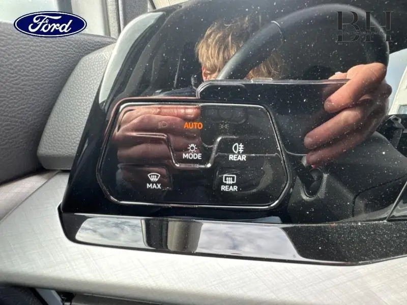 Détail du panneau de commandes d’éclairage intérieur noir brillant sur Volkswagen Golf gris lunaire, avec affichage digital orange.