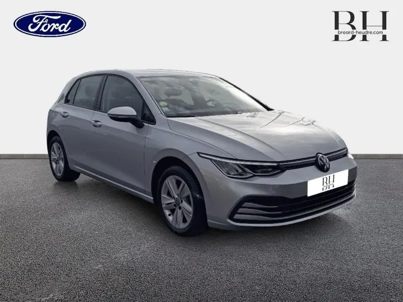 Volkswagen Golf gris lunaire vue 3/4 avant droit, avec phares LED et jantes alliage visibles.