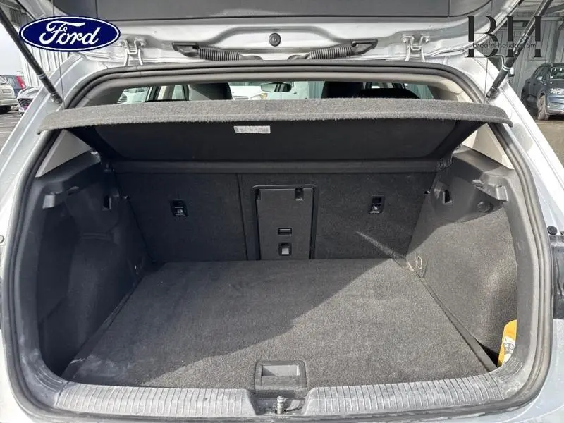 Coffre ouvert vu de l'arrière d'une Volkswagen Golf gris lunaire, montrant l'espace de chargement et la trappe à skis.