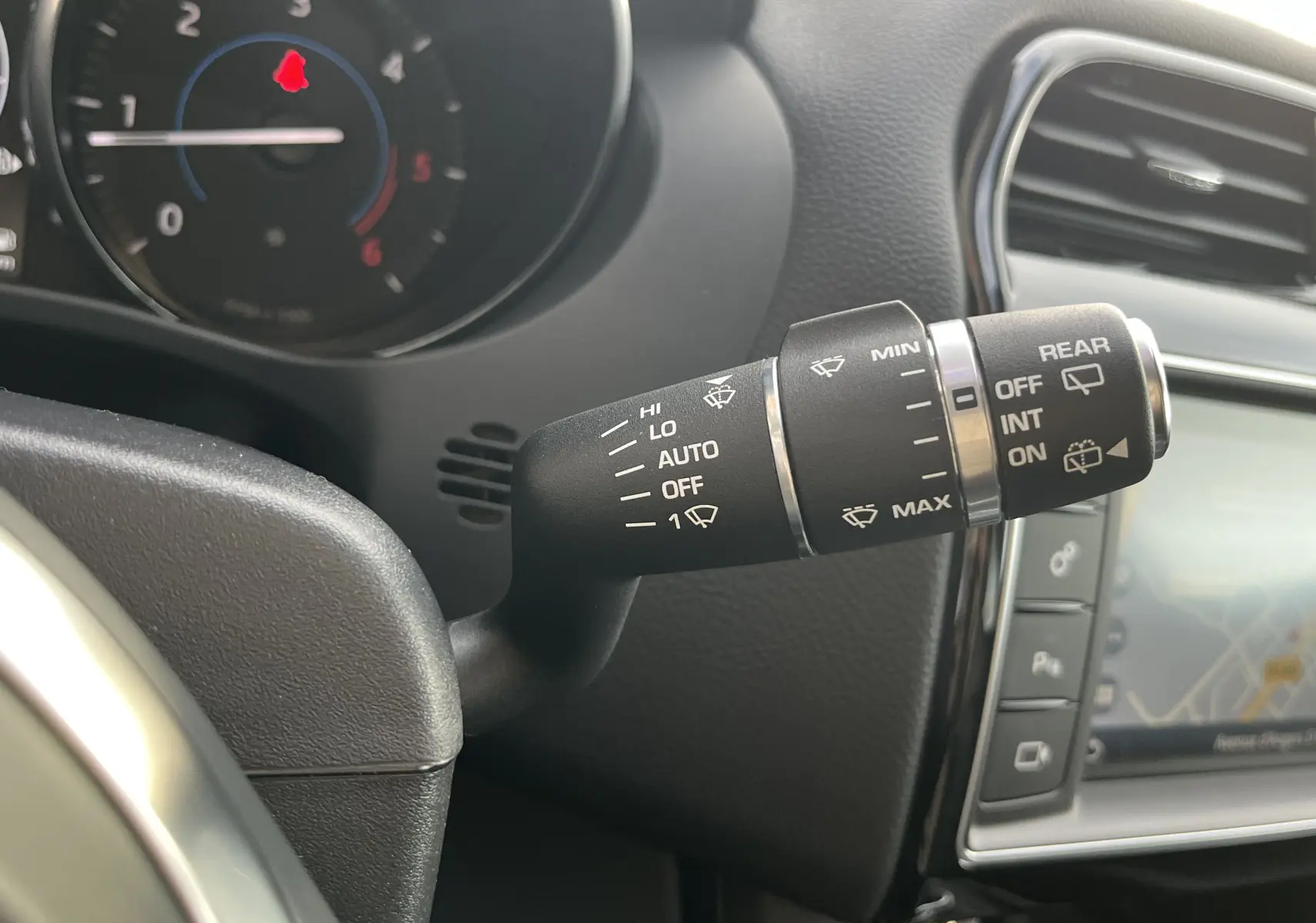 Gros plan sur la commande d’essuie-glace à gauche du volant dans l’habitacle du Jaguar F-PACE blanc 2018.