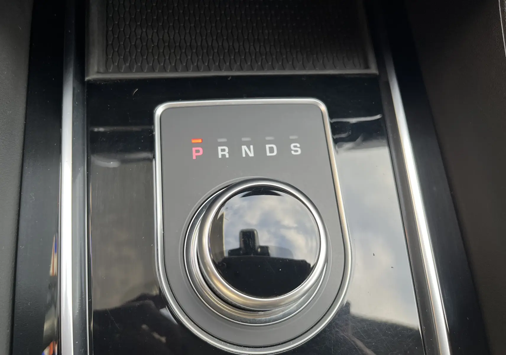 Gros plan sur la molette de sélection de vitesse du Jaguar F-PACE blanc, avec indication P en rouge sur console noire brillante.