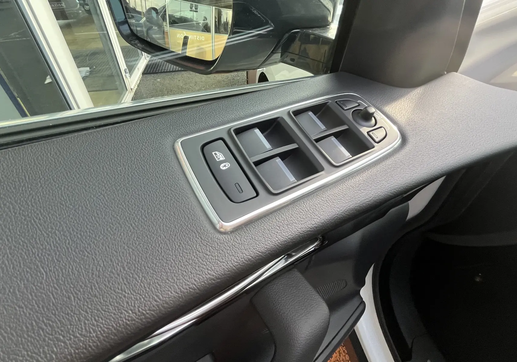 Détail des commandes des vitres sur la porte avant gauche d’un Jaguar F-PACE blanc, vue intérieure.