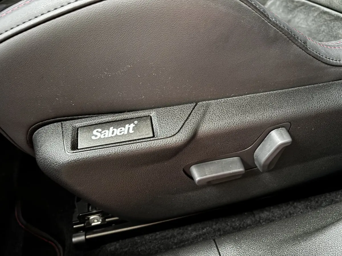 Détail du réglage de siège noir avec logo Sabelt sur Alfa Romeo Junior 1.2 Ibrida 2024, intérieur sombre.