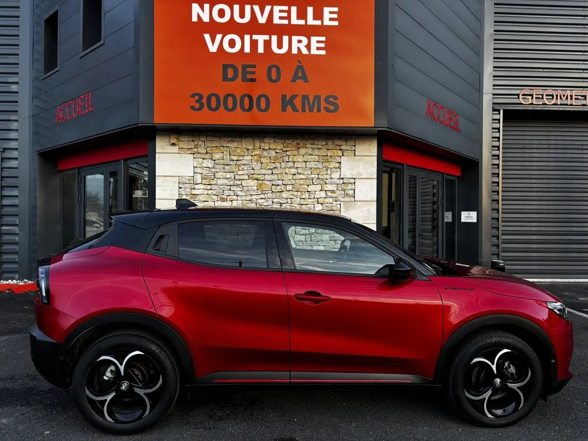 Vue latérale droite d'une Alfa Romeo Junior 1.2 Ibrida rouge 2024, avec toit noir et jantes distinctives noires et argentées.