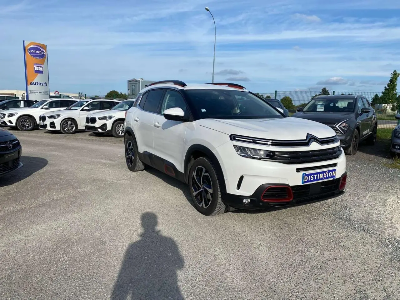 Citroën C5 Aircross blanc 3/4 avant droit avec inserts Deep Red anodisé et barres de toit bi-ton visibles.
